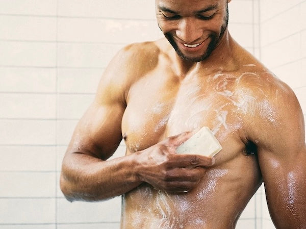 Smiling man washing body with a men's natural bar soap that creates good lather - made with organic ingredients. It's natural men's soap made affordable.