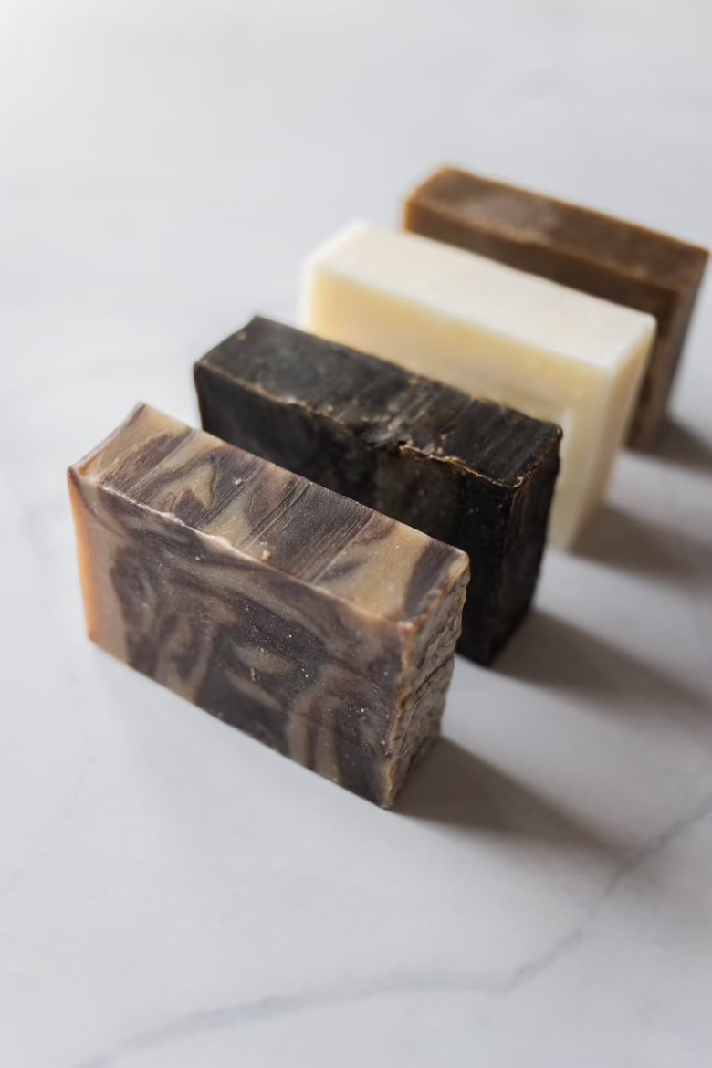 All natural men's bar soaps standing in a line on a white granite countertop.