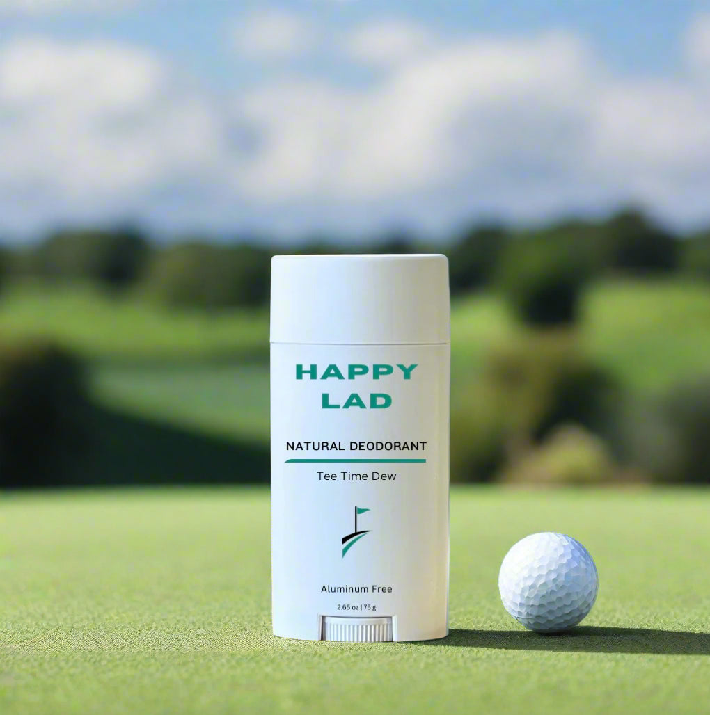 Happy Lad's aluminum free, skin safe, Tee Time Dew scented Natural Deodorant placed on a pristine fairway of a golf course with a golf ball next to it.