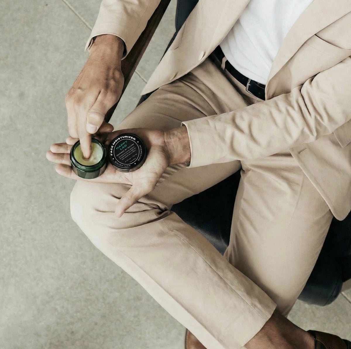 Person in a beige suit holding Happy Lad's natural face moisturizer.