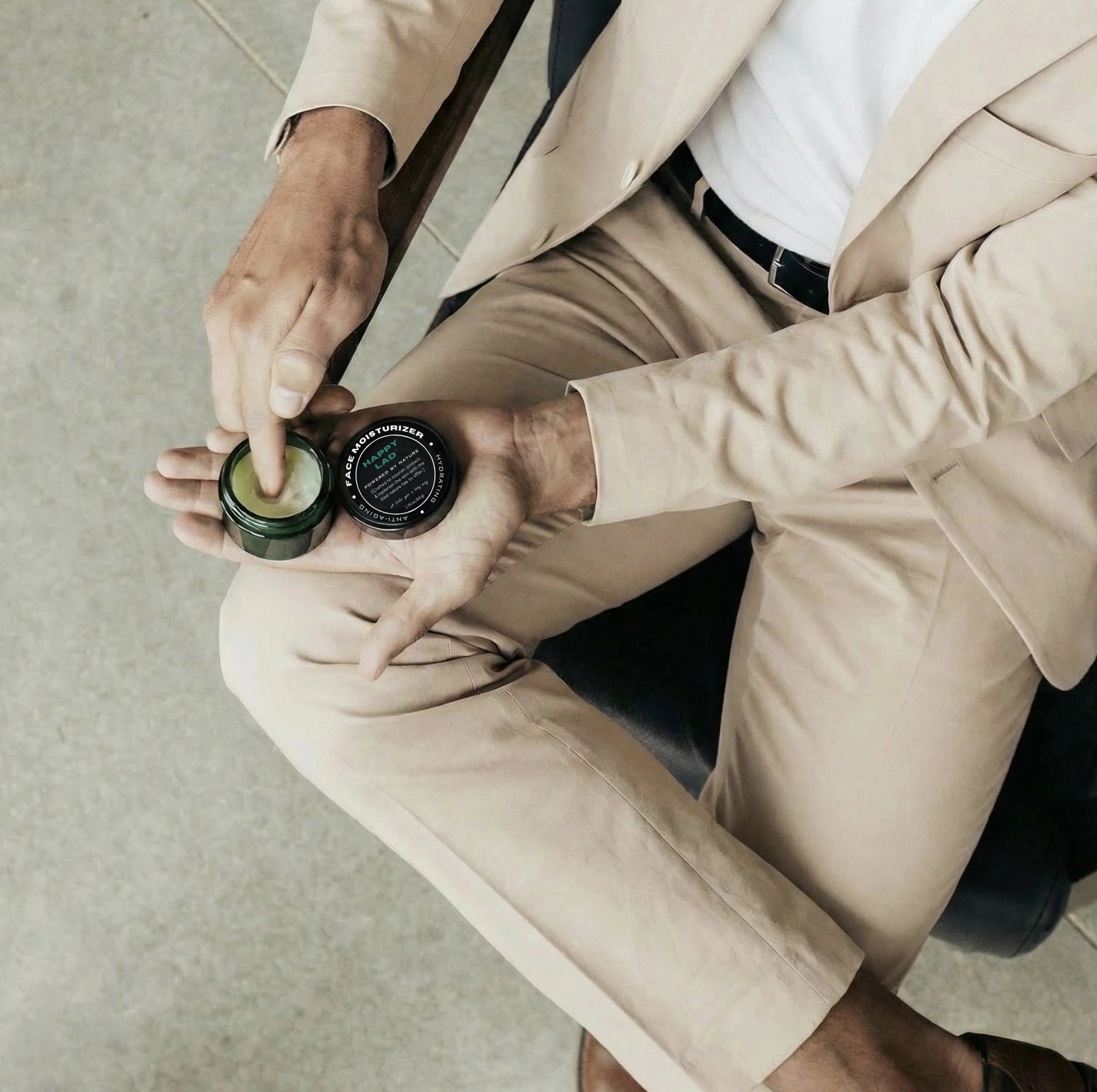 Person in a beige suit holding Happy Lad's natural face moisturizer.