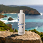 Organic mens Body Wash that is Mediterranean scented with essential oils by Happy Lad bottle on a rock with a scenic ocean view in the background.