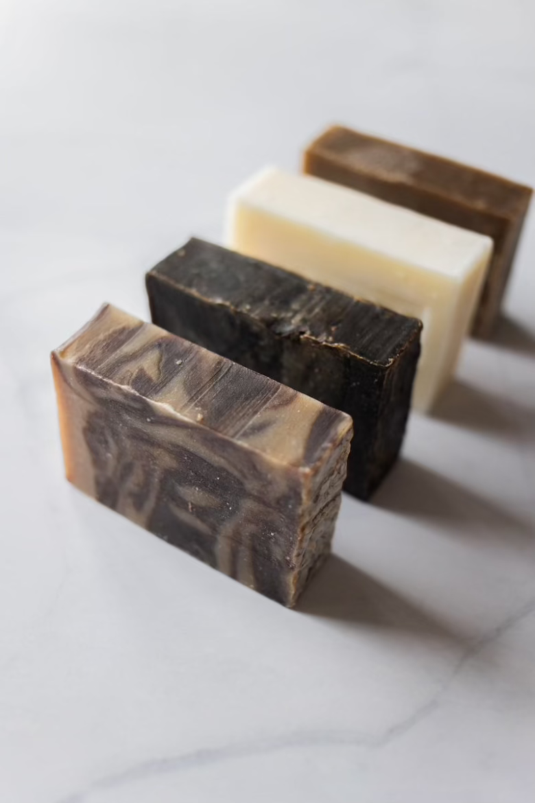 All natural bar soaps standing in a line on a white granite countertop.