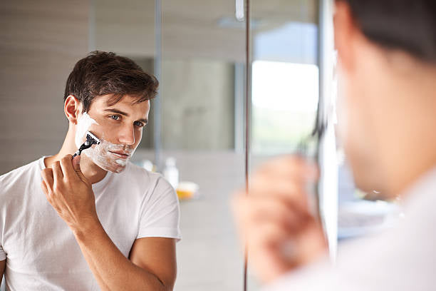 Young man shaving face with natural shaving cream.