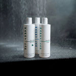 Three bottles of Happy Lad products (organic body wash and natural shampoo) on a dark marble surface with water droplets.