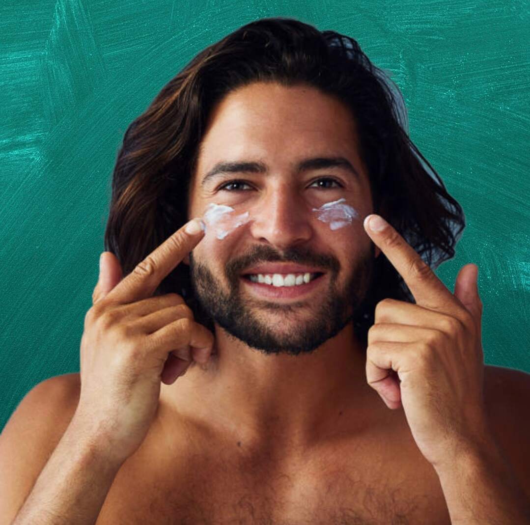 A smiling man using an all-natural face moisturizer that is free of harmful chemicals.