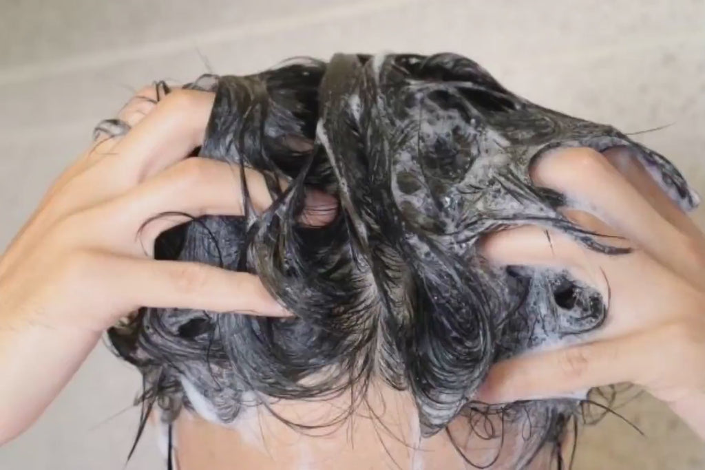 Man rubbing his hands through his hair as he uses his favorite natural shampoo for men to wash his hair